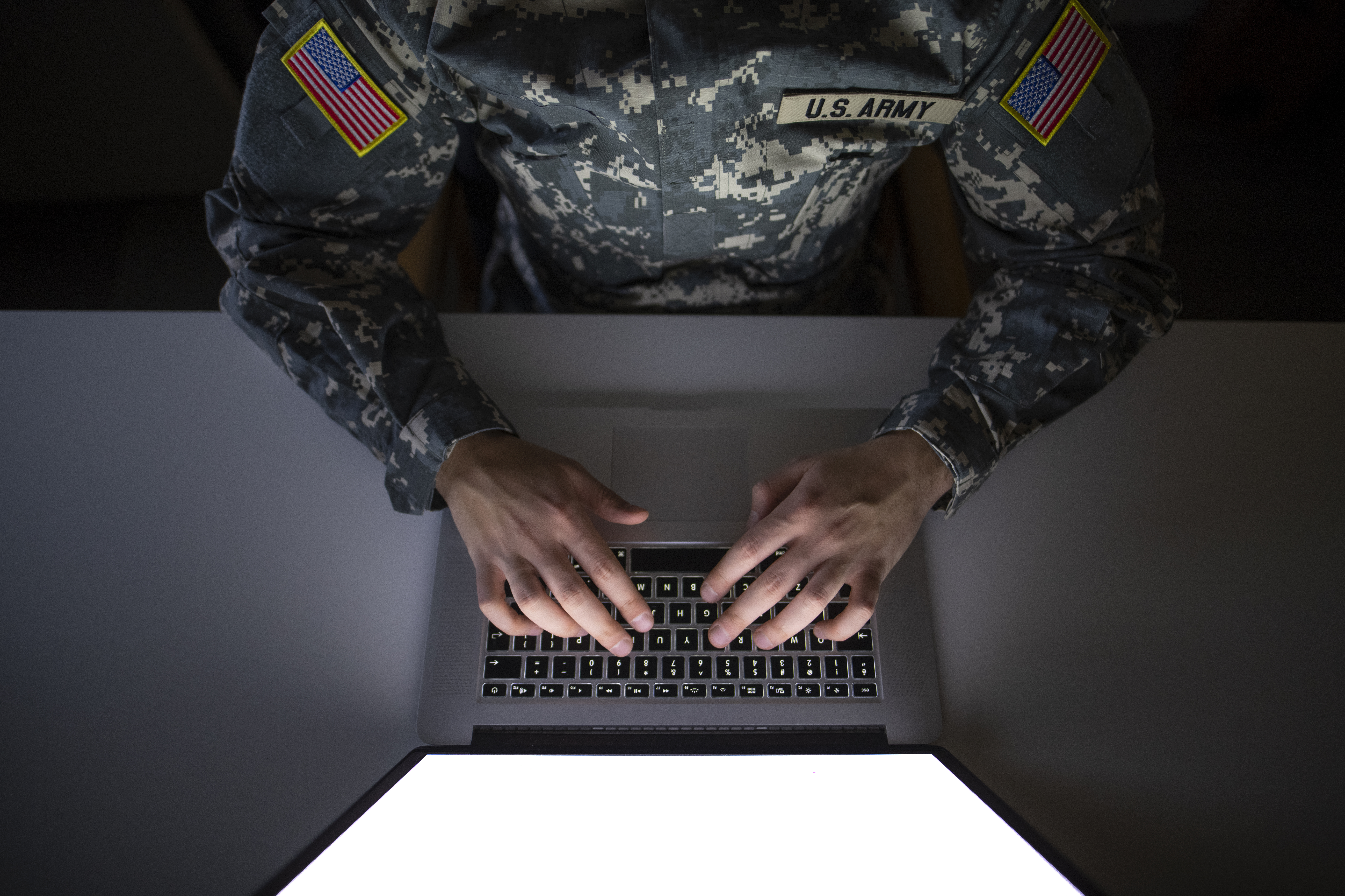 Top view of american soldier in military uniform typing on the computer.